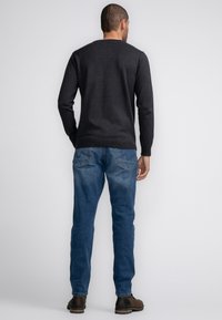 Dark gray pullover sweater with long sleeves, paired with medium blue jeans and brown boots. Smooth texture with ribbed cuffs and hem.