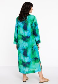 Lange kimono met een abstracte aquarelpatroon in tinten groen en blauw. Beschikt over lange mouwen en zijsplitten voor gemakkelijkere beweging.