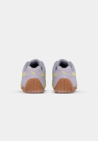 Light grey suede athletic shoes with yellow accents, textured rubber soles, and subtle branding on the heel and sides.