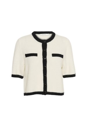 Short-sleeved cardigan, cream with black trim, featuring button closure and two front pockets. Soft texture and boxy shape.