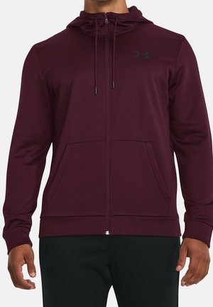 Vinrød hættetrøje med lynlås, snøre i hætten, forlommer og Under Armour-logo på venstre bryst, båret med sorte bukser.