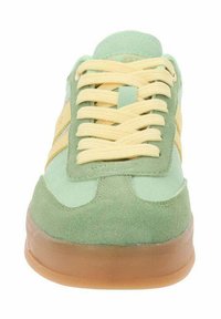 Zielone zamszowe sneakersy z żółtymi paskami, teksturowana cholewka i gumowa podeszwa. Wyposażone w płaskie żółte sznurowadła i wyściełany język dla komfortu.