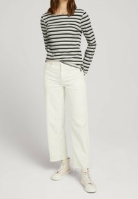 Randig långärmad topp i grått och svart, kombinerad med vita högmidjade jeans och beige ankelstövlar, med rått nederkant.