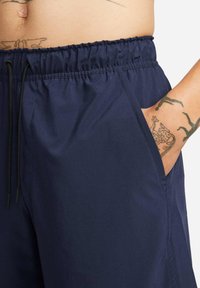 Navy blue shorts with an elastic waistband and drawstring detail, featuring side pockets and a smooth, lightweight fabric texture.