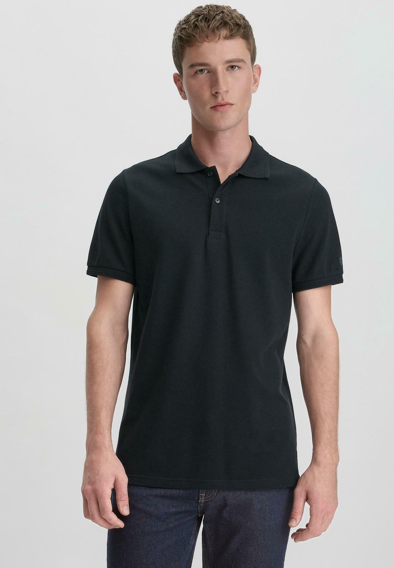 Black polo shirt made of textured cotton. Short sleeves, two-button placket, and subtle logo detail on the sleeve. Fitted design.