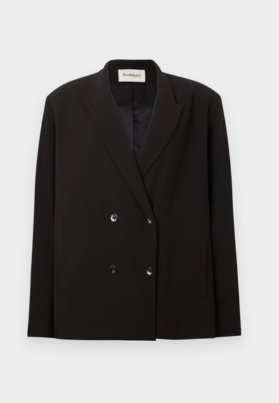 Blazer noir croisé à revers à encoche, quatre boutons sur le devant, poches latérales, et une étiquette Rodebjer à l'intérieur du col.