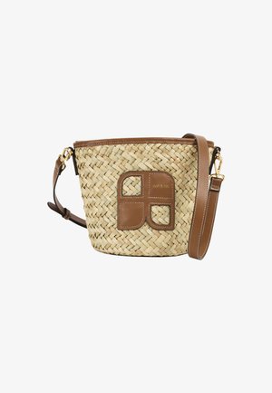 Bolso tipo cubo tejido de paja con ribete de cuero marrón, correa ajustable para el hombro y parche de cuero con diseño geométrico y texto "nat & nin".