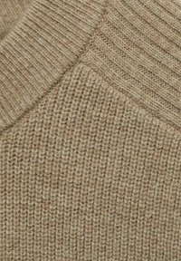 Beige gebreid stof met een geribbelde textuur en een subtiele mix van lichtere en donkere vezels. Heeft een gladde halslijn en een consistent patroon.