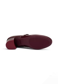 Zapato de cuero burdeos con puntera redondeada, tacón bloque y suela texturizada. Presenta un acento decorativo de hebilla en el costado.