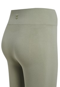 Olivgröna leggings med hög midja, som har en mjuk textur och subtil broderad detalj på baksidan.