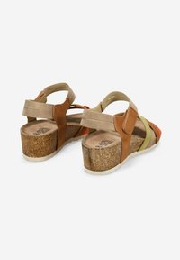 Sandalía marrón y marrón claro con tacón de corcho, con tiras cruzadas en verde, naranja y beige. Incluye correa ajustable para el tobillo.
