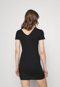 Svart randig klänning med korta ärmar och design med V-rygg, figurnära silhuett och slät textur. Inga anmärkningsvärda mönster eller hårdvara.