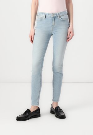 Jasnoniebieskie, dopasowane dżinsy wykonane z denimu, z wysokim stanem, pięcioma kieszeniami i przylegającym krojem, zestawione z czarnymi loafersami.
