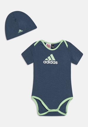 Body a maniche corte in cotone blu navy con rifiniture verde chiaro. Presenta un logo Adidas bianco sulla parte anteriore. Include un berretto abbinato.