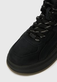 Μαύρα δερμάτινα sneakers με υφασμάτινη επιφάνεια, μαξιλαρωμένο κολάρο και αντίθετους μαύρους και λευκούς ρίγες κορδόνια, με στρογγυλή μύτη και καουτσούκ σόλ�α.