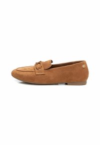 Mocasines de ante marrón con una textura suave, un accesorio de cinta en la parte delantera y un tacón bajo y plano. Presentan una punta redondeada y un pequeño detalle de logo en el lateral.