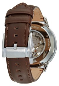 Bracelet de montre en cuir marron avec des coutures visibles et une boucle en métal argenté. Le fond de boîte transparent révèle des détails de mouvement complexes.