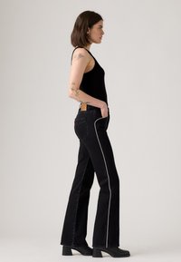 Zwarte high-waisted jeans met witte zijstrepen, gemaakt van denim. Flared leg ontwerp, met een structuurstof en leren achterpatch.