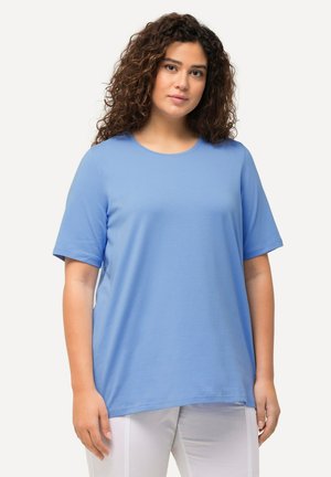 T-shirt azzurro chiaro a maniche corte in tessuto morbido con scollatura rotonda e vestibilità rilassata, abbinato a pantaloni bianchi. Senza fantasie né accenti.