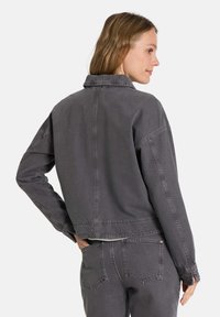 Graue Jeansjacke mit cropped Design, klassischem Kragen, langen Ärmeln und sichtbaren Nahtdetails. Texturiert und lässige Passform.