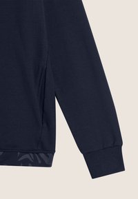 Sudadera de marina con manga y puño acanalado, que presenta un ribete texturizado en el dobladillo y una abertura lateral para mayor comodidad y estilo.