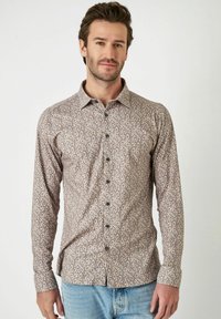Lange mouw button-up shirt in een lichtbruine stof met een paisleypatroon, voorzien van een klassieke kraag en groene knopen.