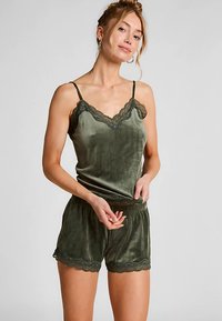 Fluwelen loungewear set in diep groen met een kanten topje met bandjes en bijpassende korte broek met elastische tailleband en decoratieve kantaccenten.