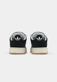 Svarte mokkasinsneakers med hvit polstret krage, med kremfarget mellomsåle og såle i gummigummi. Ikonisk tre-stripe-logo på hælen.