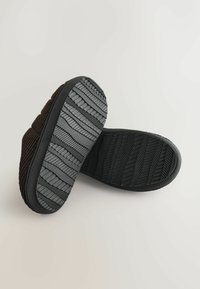 Hnedé kordové papuče s čiernou gumovou podrážkou. Podrážka je vybavená vzorom rybej kosti pre lepšiu priľnavosť a odolnosť.