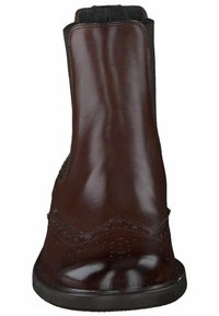 Botín de cuero marrón con detalle decorativo de brogue, textura lisa, puntera redonda, paneles laterales elásticos y suela baja de goma negra.