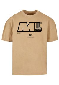 Beige puuvillainen t-paita lyhyillä hihoilla; edessä suuri musta graafinen "M" ja teksti "JCONZALES". Yksinkertainen pyöreä pääntie.