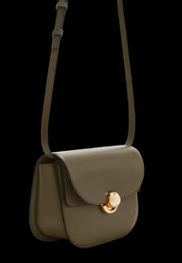 Oliveově zelená kožená kabelka obdélníkového tvaru s klopovým uzávěrem a zlatým kulatým kováním. Součástí je nastavitelný popruh.