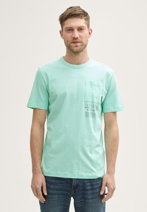 Mintgrünes Kurzarm-T-Shirt aus Baumwolle, mit einer Brusttasche und einem bedruckten Textdesign auf der linken Seite. Klassischer Rundhalsausschnitt.