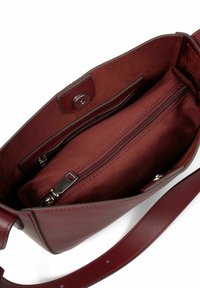 Interno della borsa in pelle bordeaux con una texture liscia. Include una tasca con zip e un compartimento in tela. Chiusura a scatto e tracolla regolabile.