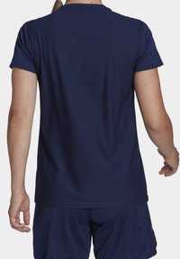 Laivastonsininen urheilupaita, jossa on lyhyet hihat, kuvioitu rakenne, pyöreä pääntie ja rento istuvuus, käytetty yhdessä vastaavien shortsejen kanssa.