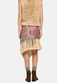 Beżowy kamizelka z futra sztucznego, spódnica w wzory w odcieniach różu i fioletu, frędzlowe wykończenie, szare skarpetki i brązowe botki za kostkę w swobodnym stroju.