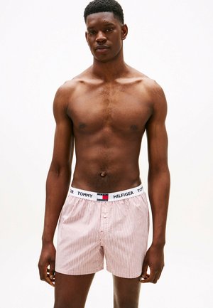Boxer da uomo a righe rosse e bianche con elastico in vita del marchio Tommy Hilfiger, dotati di patta con bottone e vestibilità comoda. Materiale in cotone morbido.