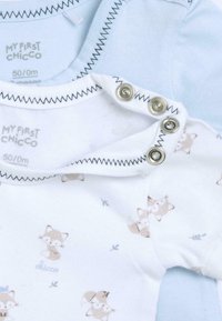 Bodies pour bébés blancs et bleu clair avec des motifs de renards, dotés de boutons-pression en métal et de coutures noires contrastantes le long de l'encolure.