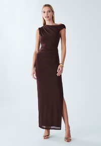 Bruine, nauwsluitende maxi-jurk met een ontwerp met één schouder, geplooide details en een hoge split tot aan de dij. Gladde stof en enkellaarzen met bandje.