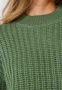 Hellgrüner gestrickter Pullover mit dickem, geripptem Design und rundem Ausschnitt. Die Struktur ist grob mit sichtbaren Stickmustern.
