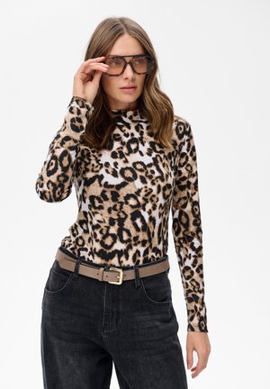 Leopardprint langemouwen top met een opstaande kraag, gemaakt van zachte stof; gecombineerd met hoge zwarte jeans en een beige riem.