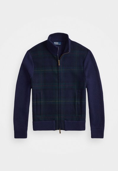Námornícka a zelená károvaná zipová bunda s vysokým golierom, pletenými rukávmi, dvoma prednými vreckami a detailom zlatého zipsu. Mäkká vlnená zmesová textúra.
