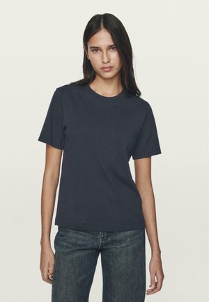 Marineblaues Baumwoll-T-Shirt mit kurzen Ärmeln, Rundhalsausschnitt, taillierter Form und weicher Textur, kombiniert mit dunkelblauen Jeans.