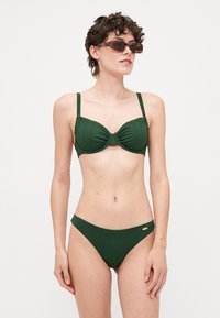 Mörkgrönt ribbat bikini med en strukturerad, formad topp och justerbara band; matchande låg midja botten med subtila guldfärgade detaljer.