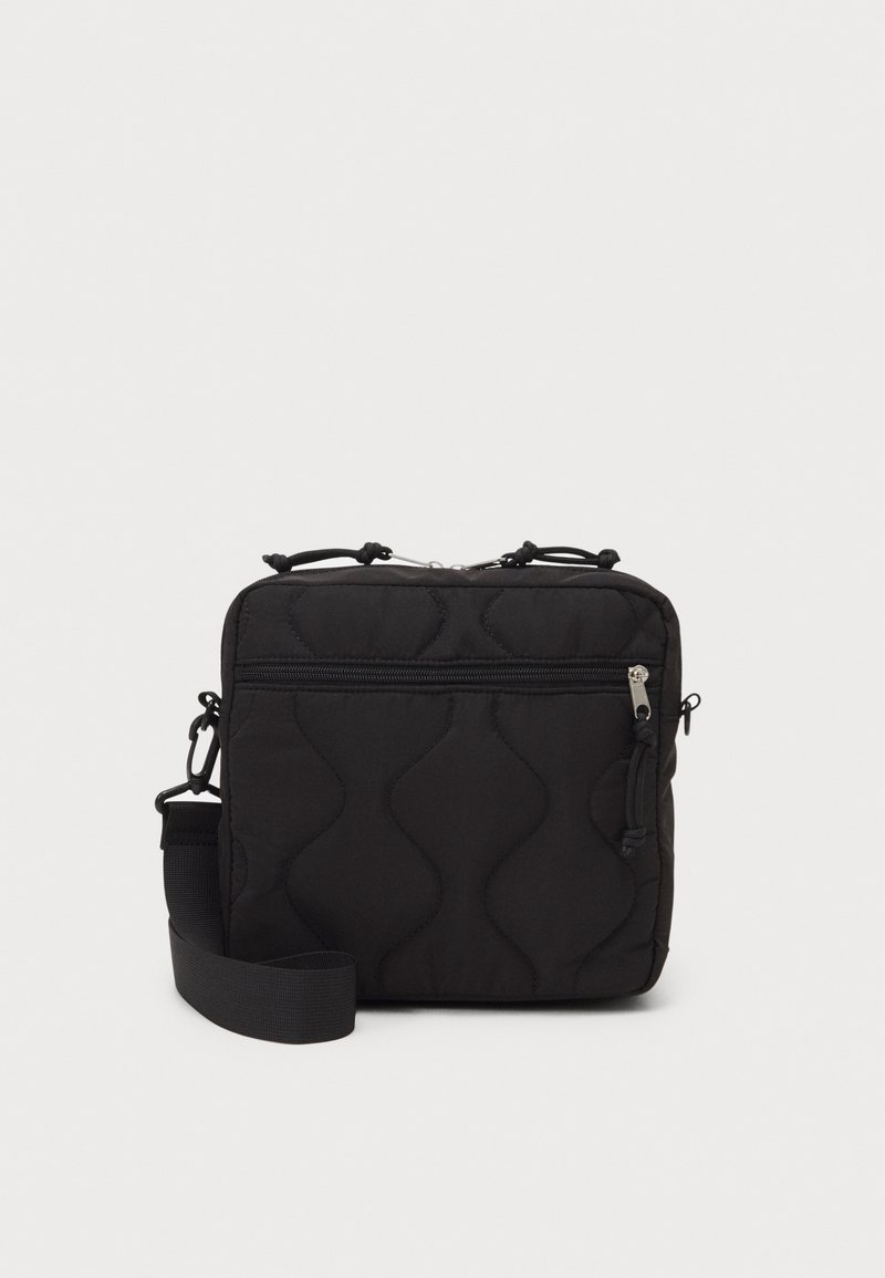 Borsa a tracolla nera trapuntata con motivo a onde testurizzate, tasca frontale con zip, tracolla regolabile e materiale in nylon.