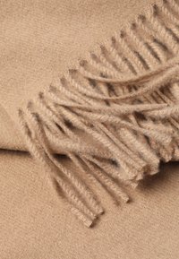 Eșarfă din lână moale, bej, cu margini franțate, întinsă pe o suprafață plată, evidențiind textura și materialul său cald și confortabil.