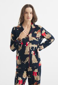 Granatowy zestaw piżamowy z wzorem w panterkę i świątecznymi akcentami, czerwonym wykończeniem, zapinana na guziki bluzka oraz dopasowane spodnie. Gładka tekstura, lekka tkanina.
