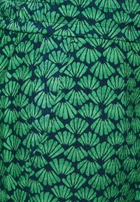 Zelená látka s opakujícím se vzorem listových tvarů na tmavě modrém pozadí, která zobrazuje texturovaný, tkaný vzhled.