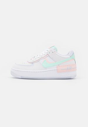 Biały trampki z pastelowymi zielonymi i różowymi akcentami, miętowym logo Nike Swoosh oraz grubą podeszwą z napisem „Air” na pięcie.