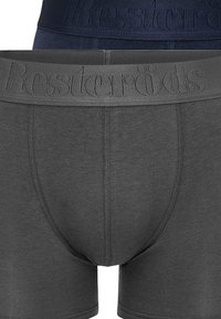 Två par herrboxershorts: ett mörkblått, ett mörkgrått. Båda har elastiska midjeband med präglat varumärkesnamn, mjukt tyg och åtsittande passform.